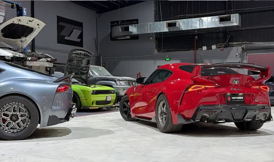 Rear of a red Supra with big wing next to a silver Supra in the bay
